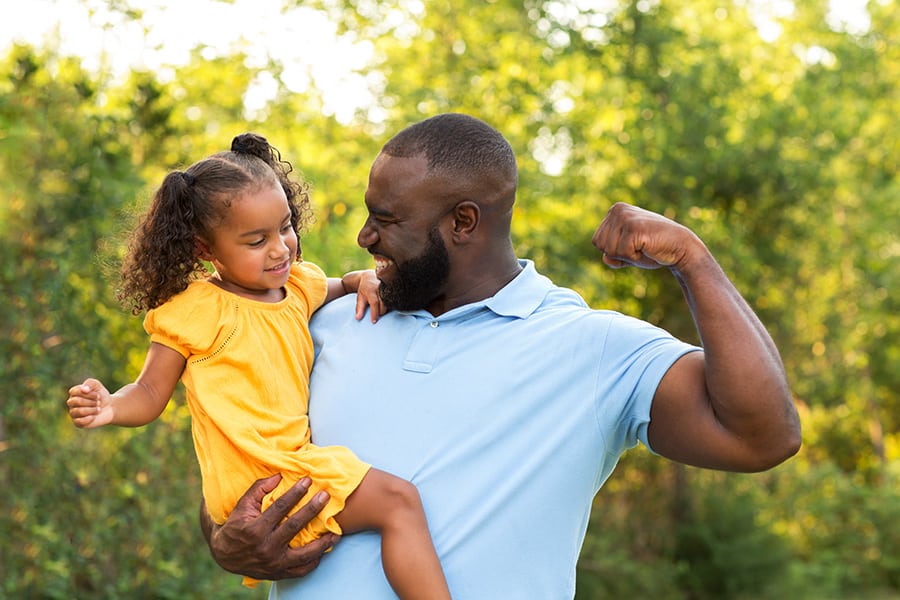 Father flexing and holding up his daughter