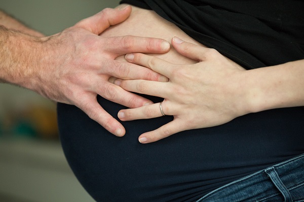 Pregnant woman holding her belly and smiling